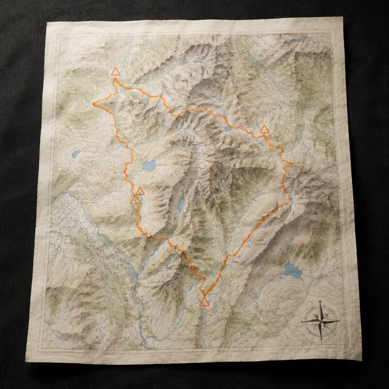Paper topographic map with hand-drawn route in signal orange and four triangle hazard markers